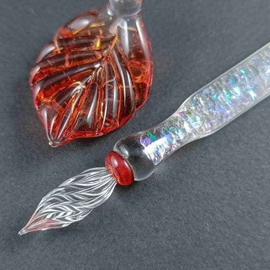 Handmade amber glass dip pen with a feathered nib and a leaf-shaped rest