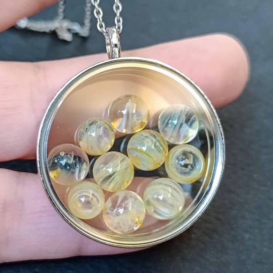 Handmade floating glass marble locket pendant resting in an open hand