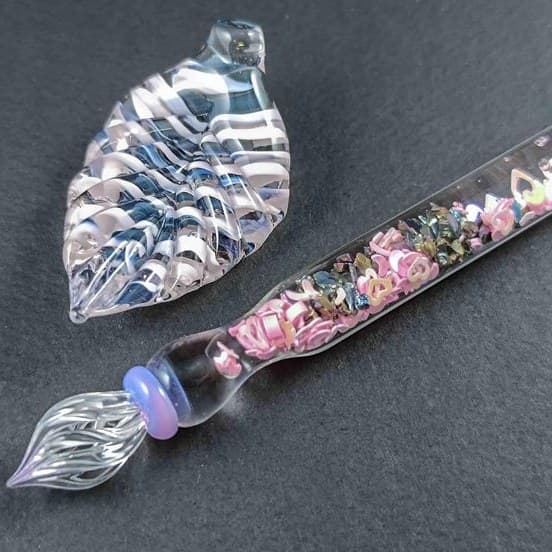 Handmade pink glass dip pen with a matching leaf-shaped rest and sparkling core, for calligraphy